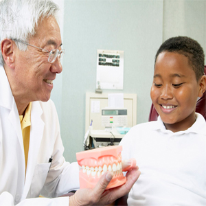 A dentist with a boy - “ We make sure our patients know how to brush their teeth.” 